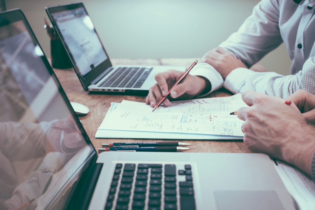 Invoices being reviewed beside a laptop